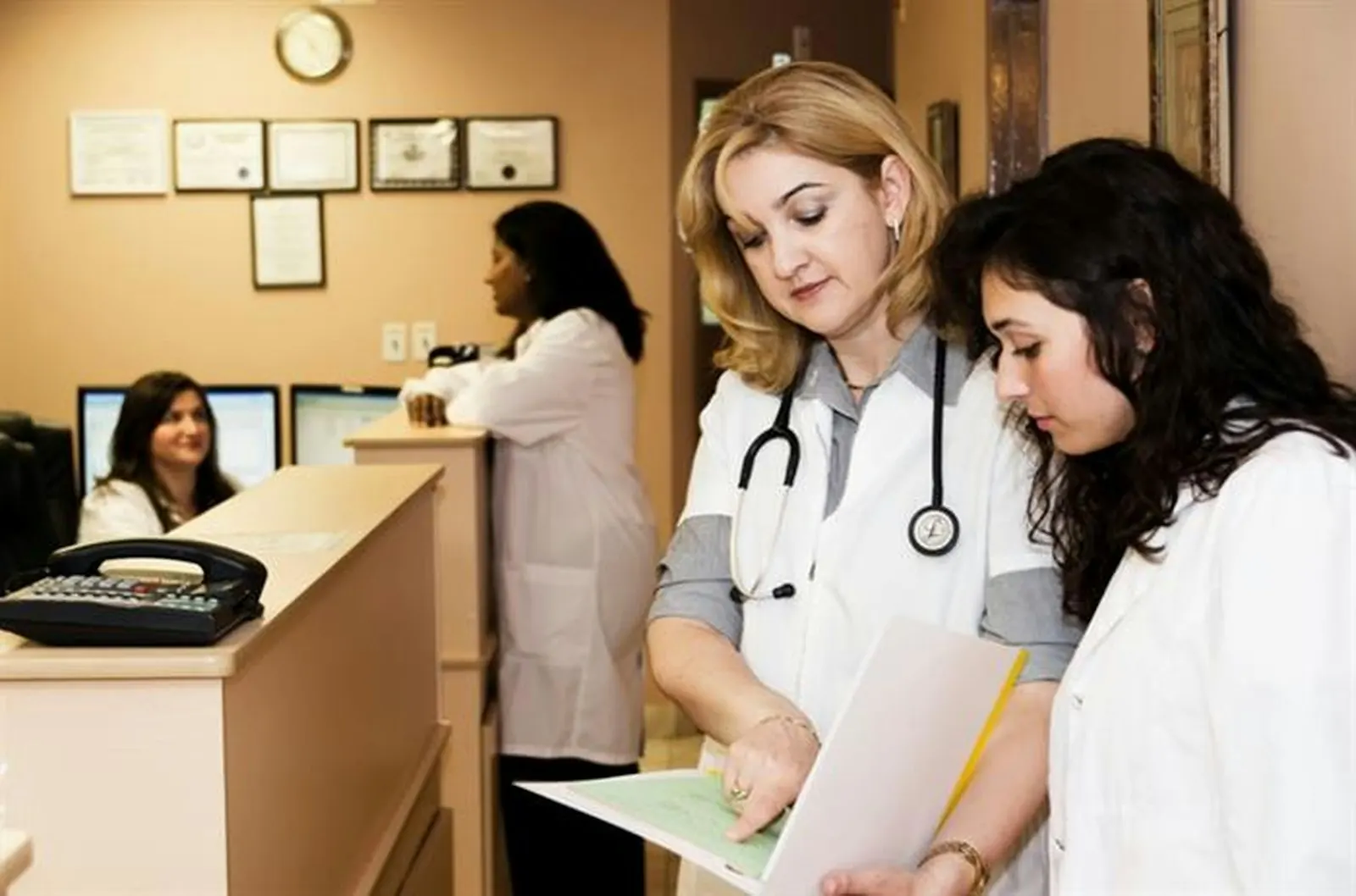 Two clinicians reviewing notes at a clinic reception desk